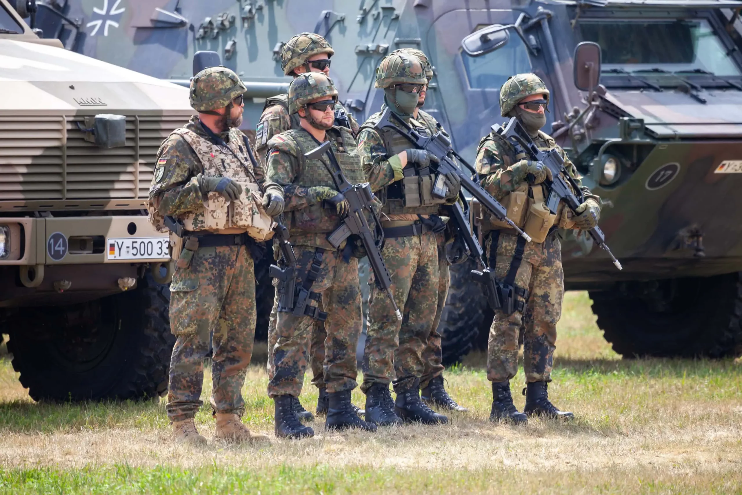 Gruppe von Bundeswehrsoldaten im Gespräch vor Fahrzeugen – Beratung aus der Praxis der Bundeswehr