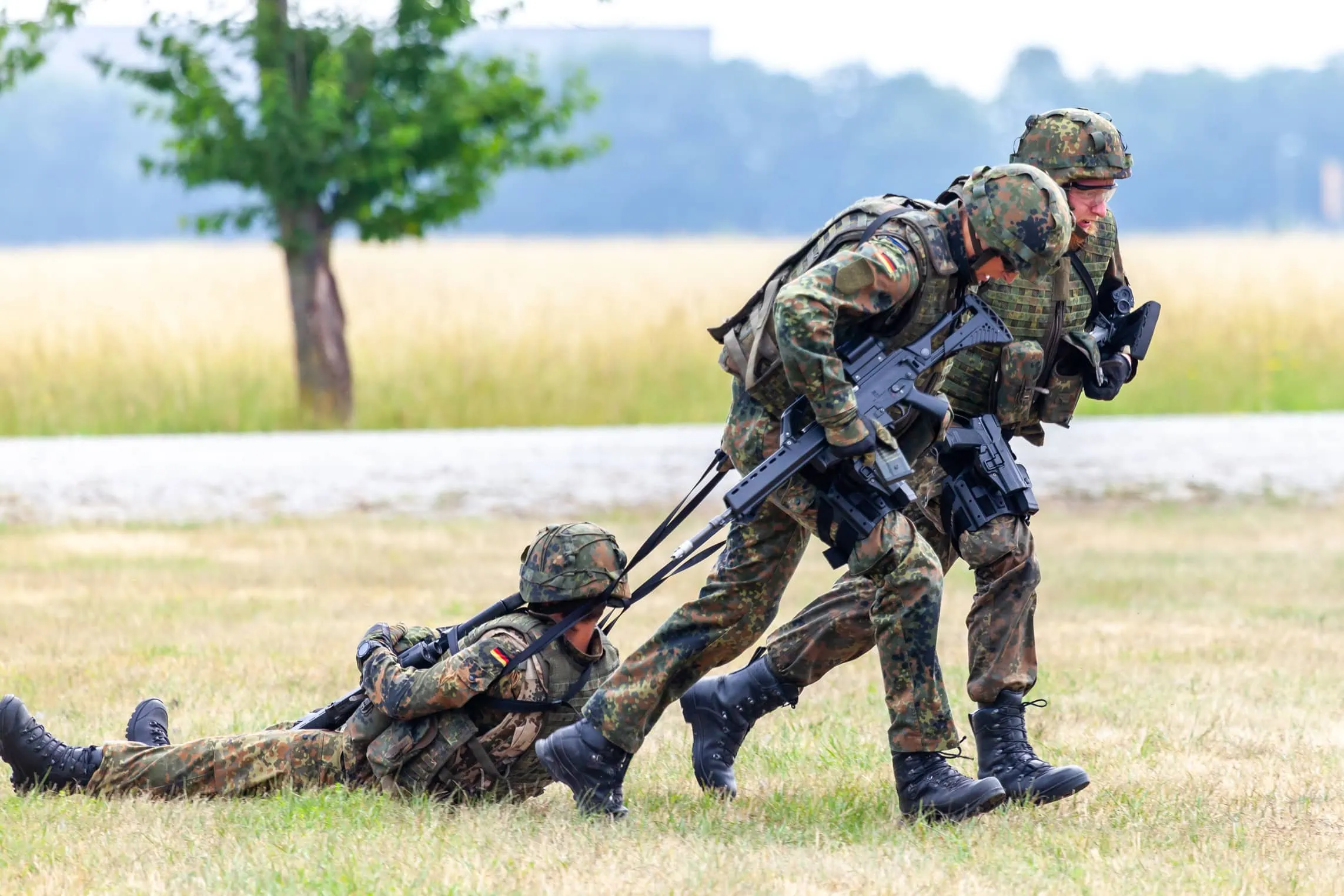 Zwei Bundeswehrsoldaten bringen einen verletzten Kameraden aus der Gefahrenzone &ndash; Sinnbild f&uuml;r Dienstunf&auml;higkeit und Absicherung